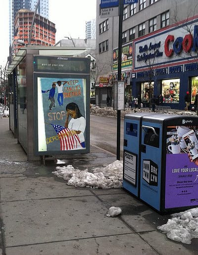 poster in an city ad box has message, Keep families together - stop deportations. Image of a woman crying over the American flag and others in handcuffs.