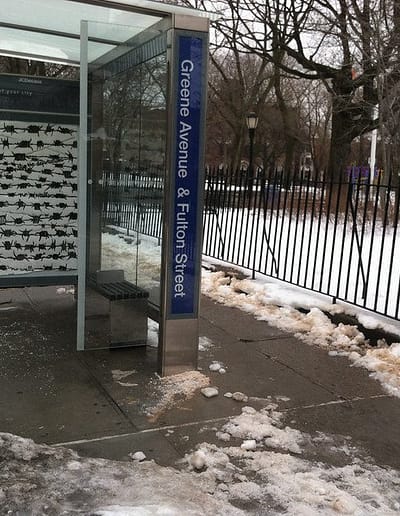 a bus stop shelter with an ad box showing a poster protesting war.